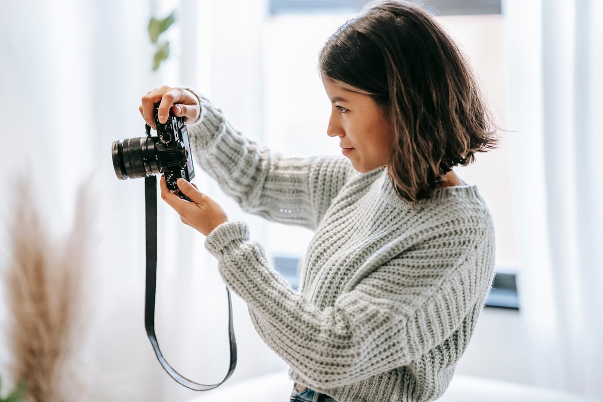 Ethnic photographer taking photo on camera in house